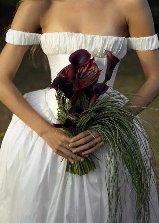 Vestido de novia de satén con hombros descubiertos, corsé estructurado y corte en A romántico, ideal para bodas al aire libre